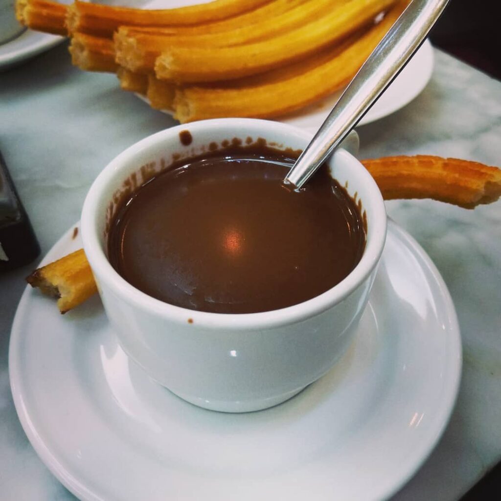 Kopp med tykk varm sjokolade og churros