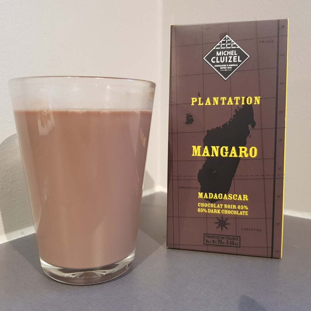 Glass med varm sjokolade ved siden av Michel Cluizel Mangaro