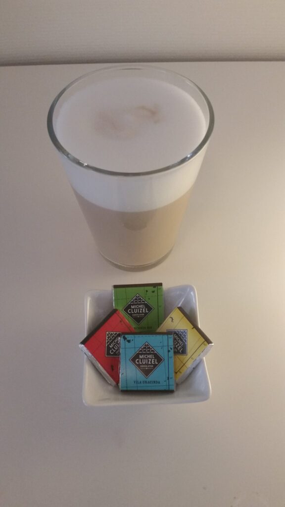 Glass med caffe latte og små sjokoladebiter fra Michel Cluizel
