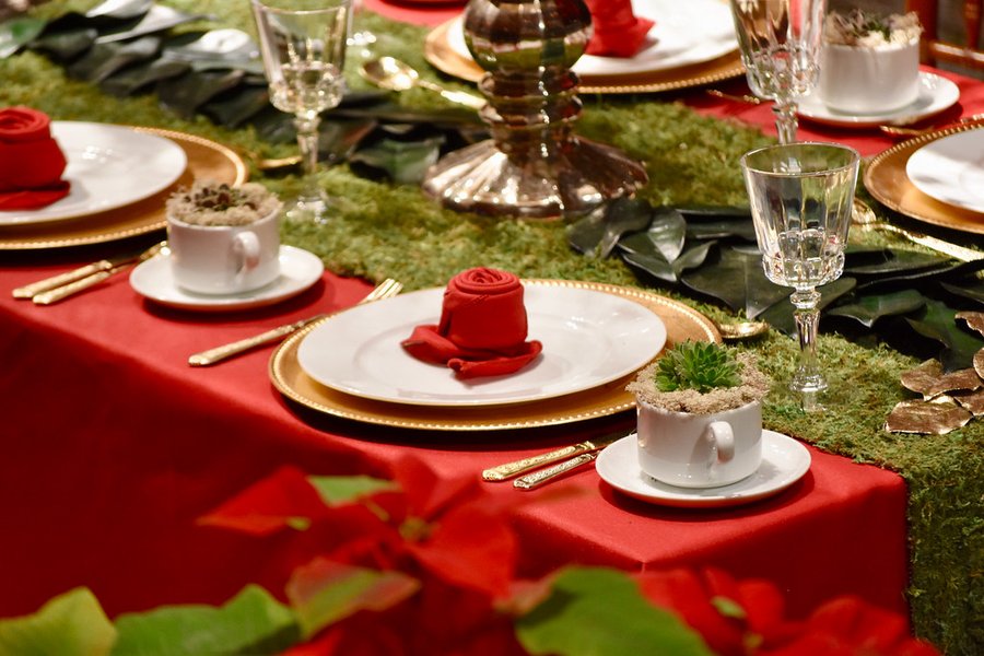 Dekket julebord med røde servietter, julestjerner og gullkantede tallerkener